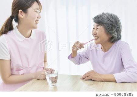 シニアの歯磨き指導をする若い歯科衛生士 90958885