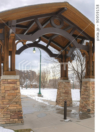 Vertical A beautiful architecture of an open waiting shed with a green lamp post behind it 90959158