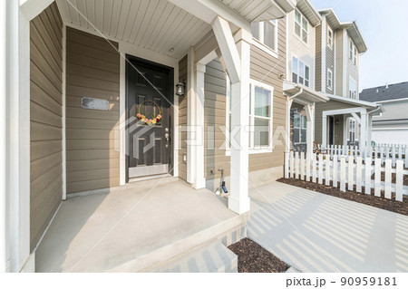 Front porch exterior of a house with white fence black door and wreath 90959181