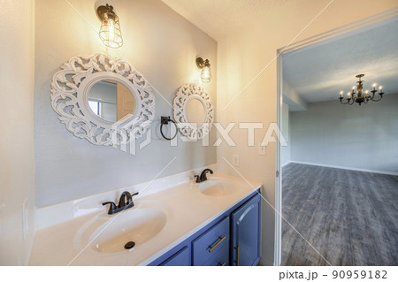 Interior of a house with a view of double vanity sink and an empty room with antique chandelier 90959182