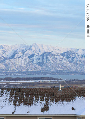 Vertical A view of the snow-covered mountains behind some house roofs 90959193