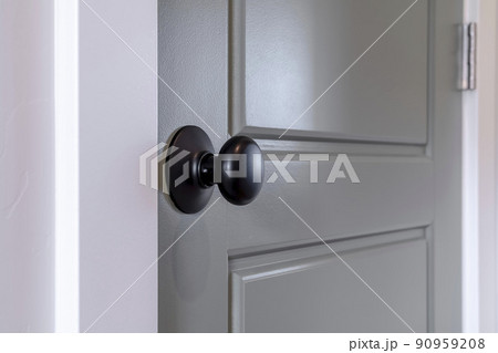Gray wooden hinged door with black door knob and panels inside of home Gray wooden hinged door with black door knob and panels inside of home 90959208