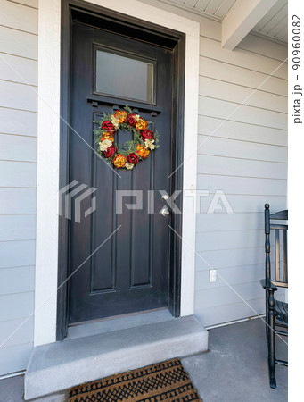 Vertical Small porch of a traditional house with black front door with wreath and black rocking chair 90960082
