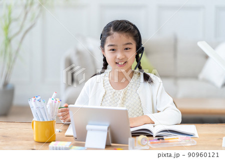 タブレットを見ながら勉強する小学生の女の子 タブレットを見ながら勉強する小学生の女の子 90960121