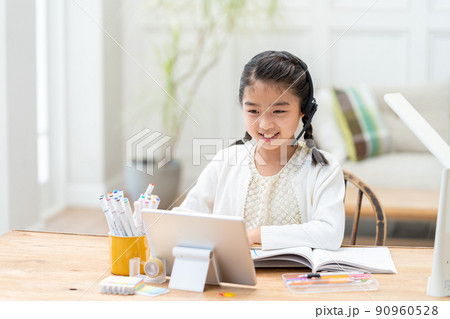タブレットを見ながら勉強する小学生の女の子 タブレットを見ながら勉強する小学生の女の子 90960528