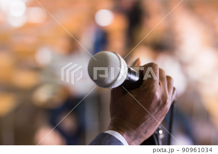 Male hand holding microphone at conference hall Male hand holding microphone at conference hall 90961034