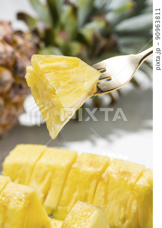 カットしたパイナップルをフォークで食べる 90963811