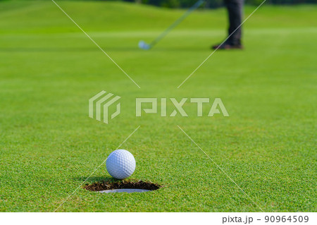 Golfer putt golf ball into hole on the green at golf course 90964509
