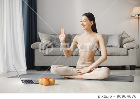Slim and beautiful woman wearing beige leggins and top and sitting on yoga mat. Young girl with fit body posing at home with fresh apples. Sport, fitness, diet, nutrition and health care concept. Slim and beautiful woman wearing beige leggins and top and sitting on yoga mat. Young girl with fit body posing at home with fresh apples. Sport, fitness, diet, nutrition and health care concept. 90964676