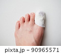ガーゼ、包帯を巻かれた女性の足先。親指の怪我 90965571