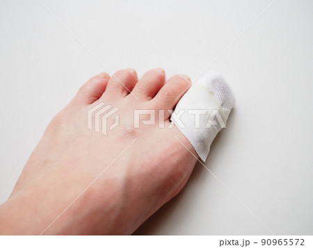 ガーゼ、包帯を巻かれた女性の足先。親指の怪我 90965572