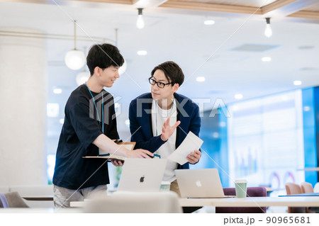 オフィスカジュアルで仕事を教えてもらう新人と教える上司 90965681