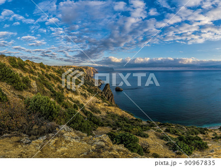 Summer seascape with Fiolent rocks formation on the coast of Sevastopol. view on cape in the sea, clear azure water, calm hot day. Copy space. The concept of calmness, silence and unity with nature. Summer seascape with Fiolent rocks formation on the coast of Sevastopol. view on cape in the sea, clear azure water, calm hot day. Copy space. The concept of calmness, silence and unity with nature. 90967835