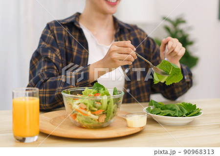 Lifestyle in living room concept, Young Asian woman looking at tablet and eating vegetable salad 90968313