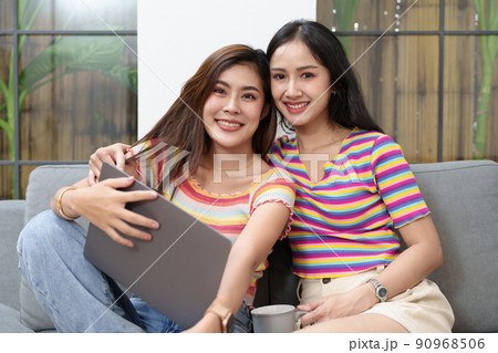 lgbtq, lgbt concept, homosexuality, portrait of two asian women posing happy together and loving each other while playing computer laptop on bed. 90968506