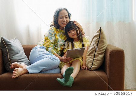 Asian portrait, Grandma and granddaughter doing recreational activities playing tablet computers on the sofa. 90968617