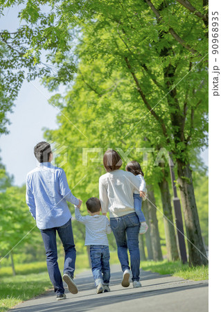 新緑の公園を歩く4人家族の後ろ姿 90968935
