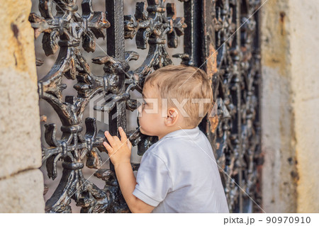 Boy peeking through a hole in the fence Boy peeking through a hole in the fence 90970910