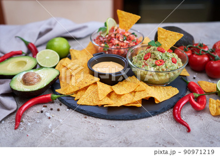 freshly made salsa and guacamole dip sauce with nacho chips on stone serving board 90971219