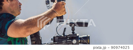 Steadicam operator and his assistant prepare camera and 3-axis stabilizer-gimbal for a commercial shoot BANNER, LONG FORMAT 90974025