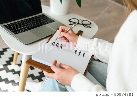 Woman writes in notebook with laptop Woman writes in notebook with laptop 90974281