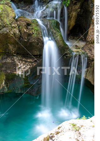 Beautiful image of blurred stream of waterfalls falling over mossy rocks Beautiful image of blurred stream of waterfalls falling over mossy rocks 90975592
