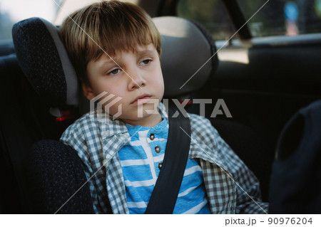 Little boy feeling sick travelling by car sitting in child seat fastened with belt Little boy feeling sick travelling by car sitting in child seat fastened with belt 90976204