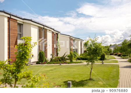 Row of modern cottages. Brand new row of single family houses. Modern design of urban living residences with private courtyards, sophisticated finishes, new development. Green outdoor facilities, lawn Row of modern cottages. Brand new row of single family houses. Modern design of urban living residences with private courtyards, sophisticated finishes, new development. Green outdoor facilities, lawn 90976880
