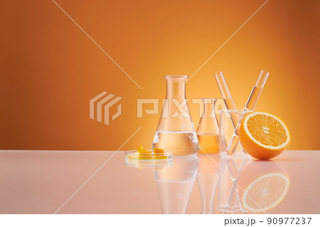 Front view of orange decorated with glassware and transparent podium in brown background  90977237