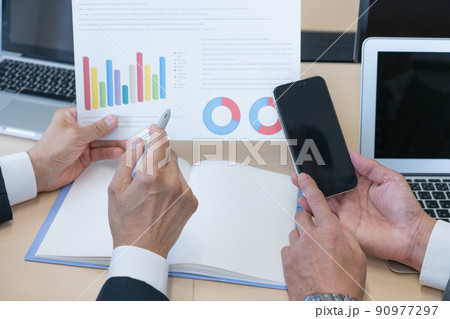 資料を見ながら打ち合わせをするビジネスマンの手元のアップ 90977297
