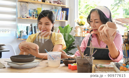 Middle agd woman painting on handicraft crockery at art workshop. Retirement, leisure activity, handicraft, hobbies concept Middle agd woman painting on handicraft crockery at art workshop. Retirement, leisure activity, handicraft, hobbies concept 90977615