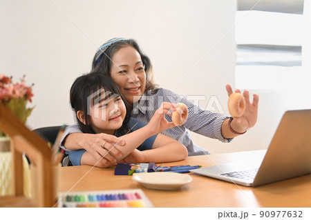 Loving mature grandma and little grandchild having video call on laptop computer at home together. Multi generational, family and love concept Loving mature grandma and little grandchild having video call on laptop computer at home together. Multi generational, family and love concept 90977632