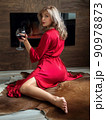 Woman sitting by fireplace with glass of wine 90978873