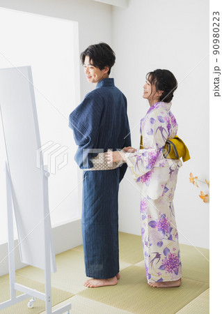 浴衣を着付けるカップル 90980223