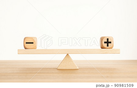 Plus and minus balance concept. Positive and negative symbols on wooden blocks are in balance on a wooden seesaw. Copy space 90981509