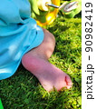 cute little baby feet on summer green grass. Pink, delicate skin of the heel, against the background of a bicycle. Summer, day, bright sun. 4k video 90982419