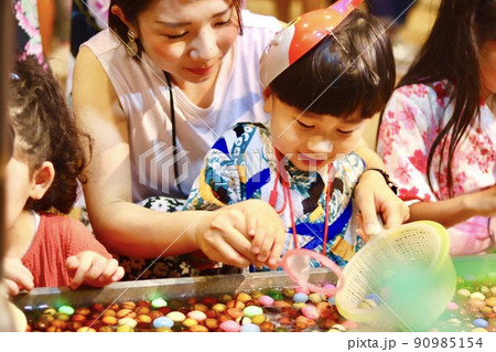 お祭りでボールすくいをする親子 90985154