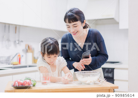 ママとスマホでレシピを見ながら料理をする娘 90985614