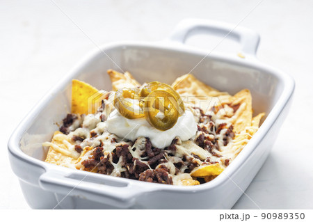 nachos with beef minced meat and cheese served with whipped cream and jalapenos nachos with beef minced meat and cheese served with whipped cream and jalapenos 90989350