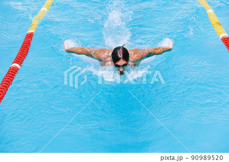 Young muscular man, professional swimmer in goggles training at public swimming-pool, outdoors. Sport, power, energy, style, hobby concept. Young muscular man, professional swimmer in goggles training at public swimming-pool, outdoors. Sport, power, energy, style, hobby concept. 90989520
