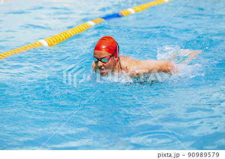 One female swimmer in swimming cap and goggles training at pool, outdoors. Healthy lifestyle, power, energy, sports movement concept. 90989579