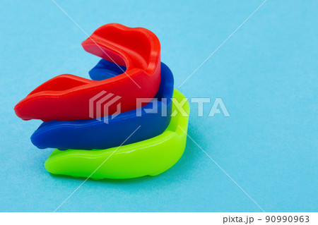 three boxing mouth guards in blue, red and green, lie one on top of the other 90990963