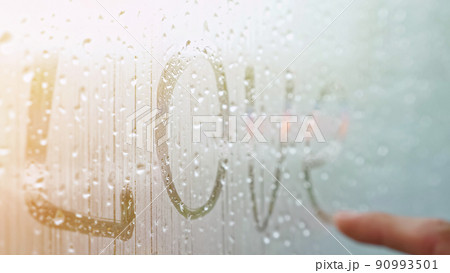 Man finger writes word Love on window covered with fog Man finger writes word Love on window covered with fog 90993501