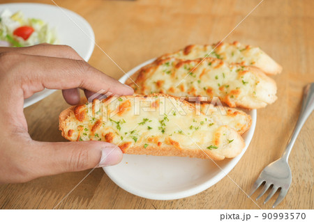 hand pick a garlic bread on a plate  90993570