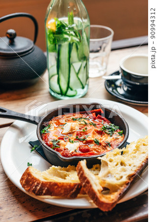 Shakshuka in iron pan served with bread Shakshuka in iron pan served with bread 90994312