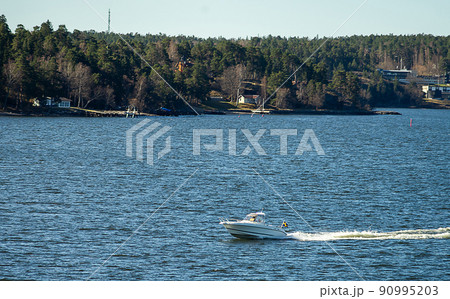 Speedboat in the strait between the islands of the Stockholm archipelago. Speedboat in the strait between the islands of the Stockholm archipelago. 90995203