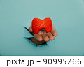 Male hand showing a thyroid out of a hole torn in blue paper wall. Health care, pharmaceutics and medicine advertisement 90995266