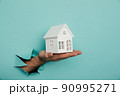 Man's hand with house through a hole in blue paper. House sale and rent concept 90995271