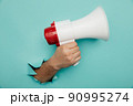 Man's hand arm hold megaphone isolated through torn blue background 90995274
