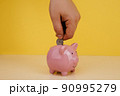 Hand is putting coin into piggy bank. Saving money or investment concept 90995279